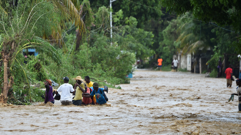 People try to cross the overflowing La Rouyonne river in the commune of Leogane, south of Port-au-Prince, October 5, 2016. Haiti and the eastern tip of Cuba — blasted by Matthew on October 4, 2016 — began the messy and probably grim task of assessing the storm’s toll. Matthew hit them as a Category Four hurricane but has since been downgraded to three, on a scale of five, by the US National Hurricane Center (Image: Getty)